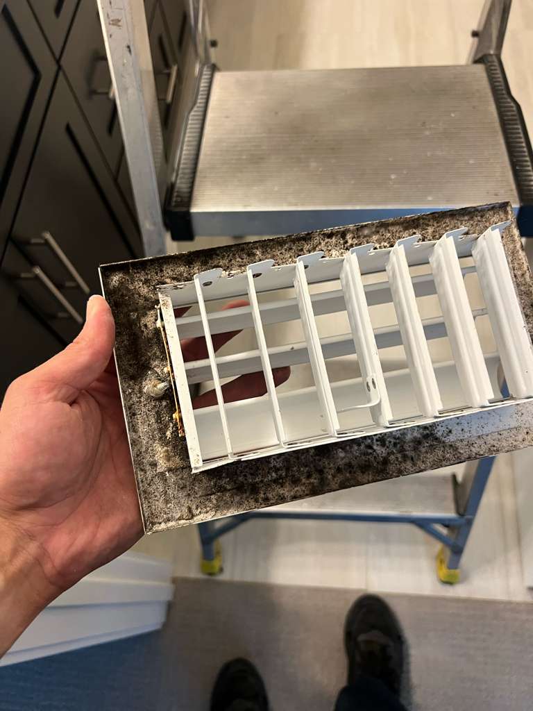 Homeowner pointing to dusty vent cover indicating need for air duct cleaning Orlando